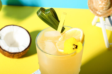 Fresh summer cocktail with lemon and flower on yellow table near blue wall