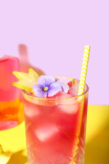 Fresh summer cocktail with carambola and flower on yellow table near lilac wall