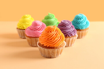 Tasty colorful cupcakes on orange background