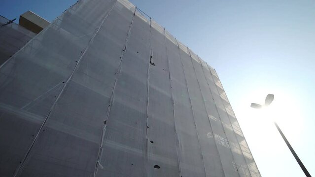 Building scaffolding covered with white protective fabric