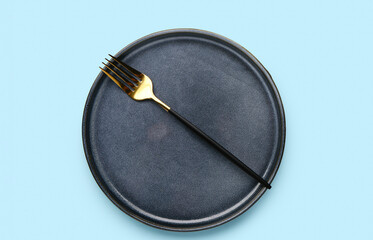 Plate with stainless steel fork on blue background