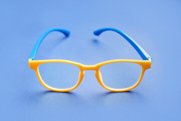 Fototapeta premium Stylish yellow eyeglasses on blue background