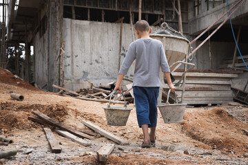  Poor little boy working at construction site, human trafficking, poor child labor. World day against child labour concept.