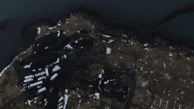 Bird's eye view aerial pullback reveals home compounds on black sand water banks