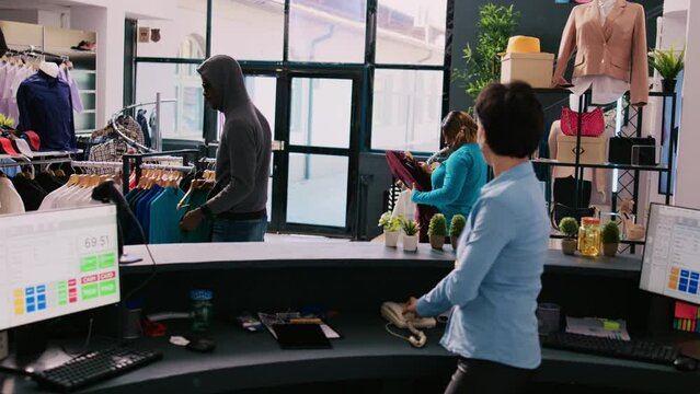 African american robber shoplifting stylish clothes, running from shopping centre. Asian bodyguard catches thief at store door, threatens him with the police in modern boutique. Burglary concept