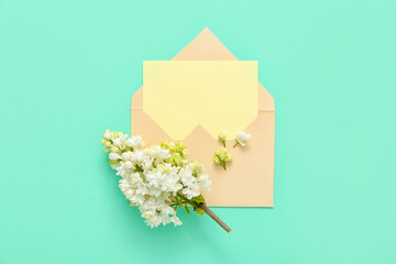 Envelope with blank card and lilac flowers on turquoise background