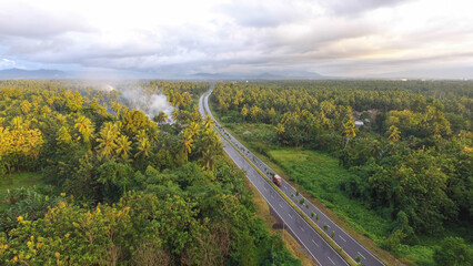 Fototapeta na wymiar Aerial photo of the highway dividing the forest and villages with a mountain background.