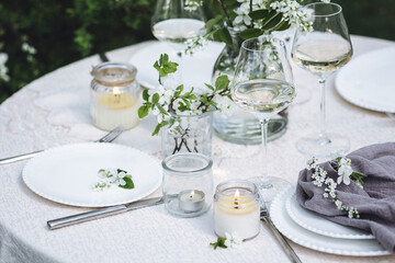 Romantic elegant luxury wedding table decor with white fresh spring blooming cherry apple tree flowers. Glass, candles, floral decoration for special marriage holiday event. No plastic zero waste