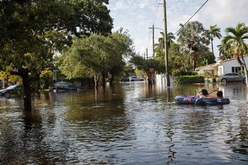COUPLE IN AN INFLATABLE RAFT NAVIGATES FLOODED STREETS