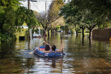 COUPLE IN AN INFLATABLE RAFT NAVIGATES FLOODED STREETS