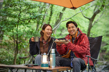 캠핑의자에 앉아 음식을 들고있는 커플 © stciel