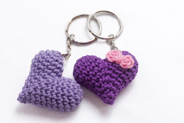 A pair of crocheted purple heart-shaped keyrings on a white background