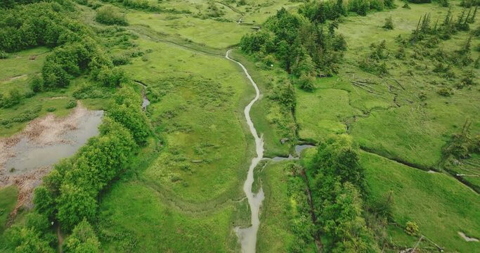 Aerial over estuary following small stream to larger rivers