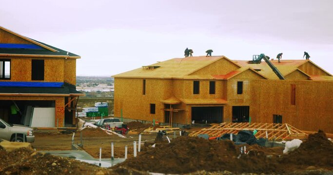Construction workers working on the roof of new being built luxury apartment condo complex - In Cinema 4K slowed half speed to 30fps.