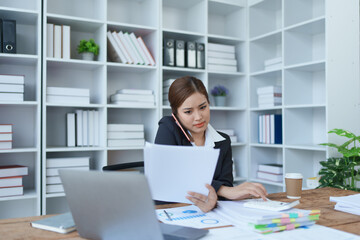 Busy businesswoman wearing a suit busy with work workaholic while sitting at work clear paperworks...