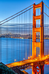 Detail of the famous Golden Gate Bridge at dawn with the skyline of San Francisco in the back