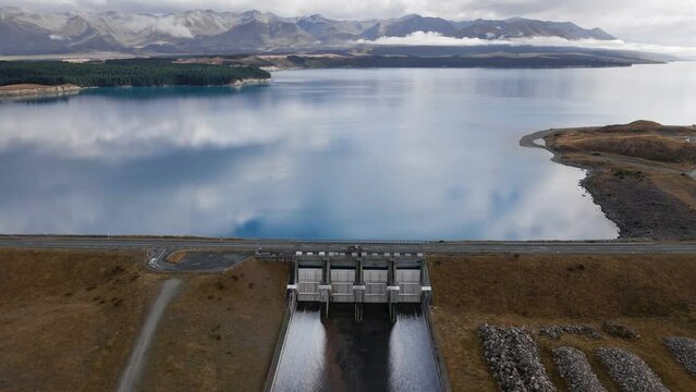Aerial - Hydro dam at alpine lake letting through glacial melt water