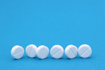 Several white pills stand on a blue background.	