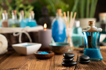 Spa and wellness concept. Bottles with bath and spa cosmetics, rolled up towels, bath salts and care products on wooden rustic paneling.