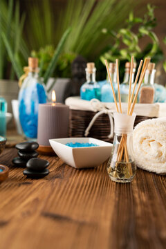 Spa and wellness concept. Bottles with bath and spa cosmetics, rolled up towels, bath salts and care products on wooden rustic paneling.