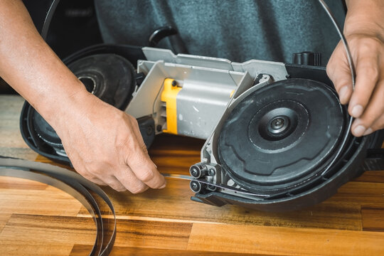 Mechanic Remove the Portable Band Saw blade on wooden desk, tool maintenance Compact Band Saws, cordless band saws