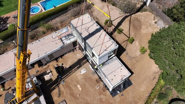 Aerial circling near crane stacking prefab house module