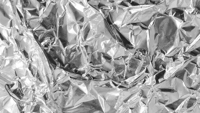 Close up of aluminium foil crumpled. Silver aluminium foil texture background. Abstract metallic paper pattern. Texture of crumpled aluminium kitchen foil rotates