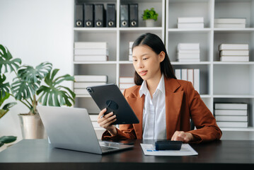  Beautiful Asian business woman typing laptop and tablet Placed at the table at the office