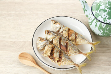 Ikan Kembung Goreng or Fried Mackerel fish, served in white plate, copy space
