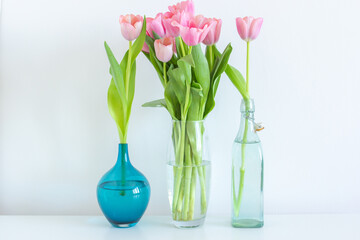 Pink tulips bouquet in glass vase on white background copy space