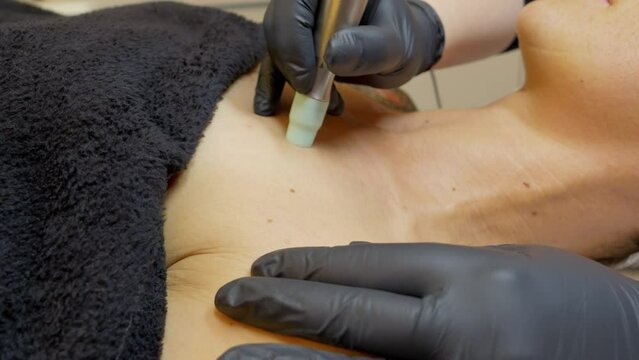 Beauty salon, a cosmetologist uses equipment to care for the skin on the patient's d&eacute;colletage