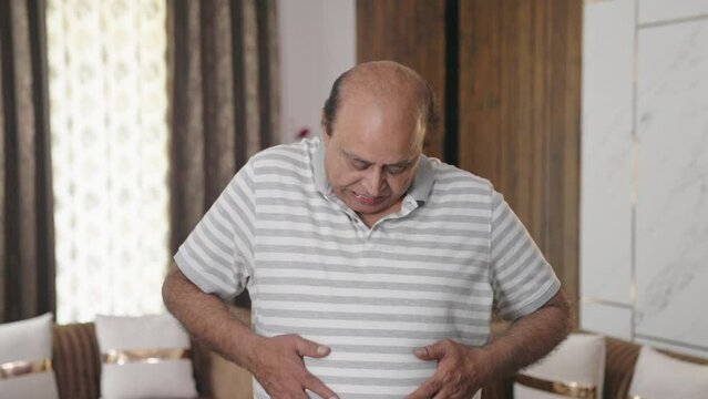 Fat Indian old man suffering from obesity and stomach pain