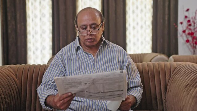 Indian old fat man reading newspaper