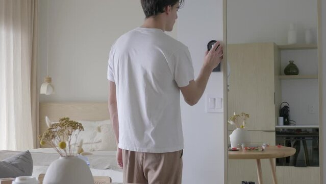 Man in Apartment Increasing the Room Temperature with Smart Thermostat