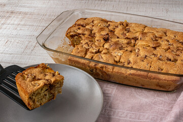 Pieces of fruit and berry pie in a glass bowl are removed with a spatula and placed on a plate. Close-up of a female hand laying pieces of apple pie on a plate. The concept of cooking pies