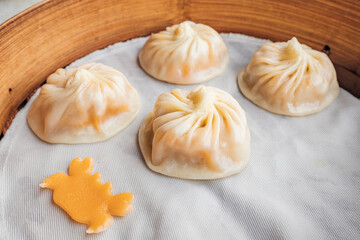 Xiao Long Bao dumplings, freshly steamed and served in a bamboo plate, making for a picture-perfect dining experience.