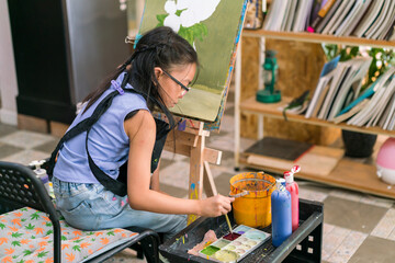 Fototapeta na wymiar Young girl asian sitting and drawing artwork to develop abilities and improve mental health at home. Female artist drawing with inspiration.