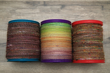 Closeup detail of a bobbin full of colourful organic natural handspun and handdyed merino sheep wool yarn , spun on a traditional spinning wheel.	