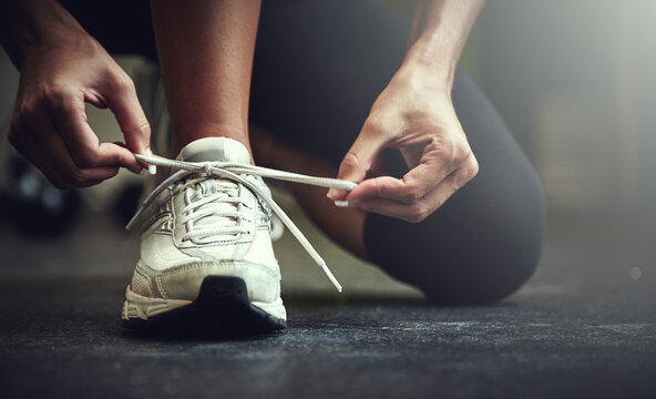 Woman tie shoe laces, hands and fitness with athlete in gym and sports with training for health. Closeup of runner sneakers, start workout in exercise studio with healthy and active female person - Powered by Adobe