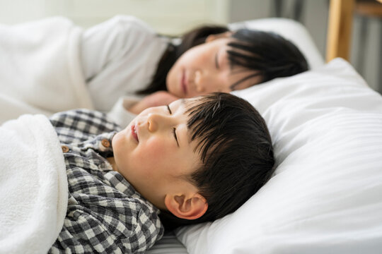 ベッドで眠る日本人姉弟