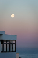 Moon over the calm sea in the morning sky with penthouse flat in foreground