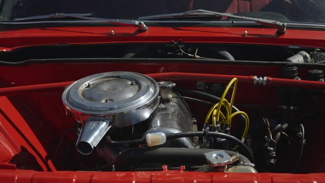 Old carburetor low power engine with shiny metal air filter cover. Sale of restored classic red youngtimer after completion of work, preparation for auction on sunlight.