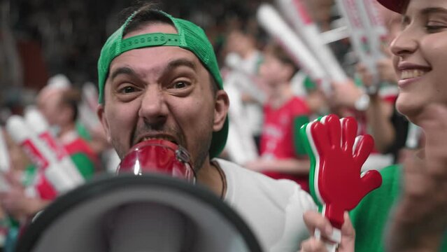 Angry man scream megaphone sport stadium. Crazy mad fan shout bullhorn closeup. Anger aggressive male cheer team goal. Furious person yell loudspeaker. Evil guy look camera. Crowd watch game cup match