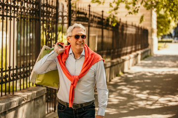 Fototapeta premium Cheerful senior adult elegantly dressed shopping in the city.