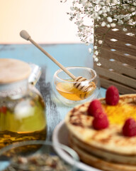 Pancakes with honey and berries for breakfast. Honey in bowl with honey dipper. Wooden background. Soft focus. Side view.