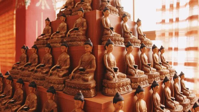 Rows of statuettes of Buddha with bowl in interior of golden abode