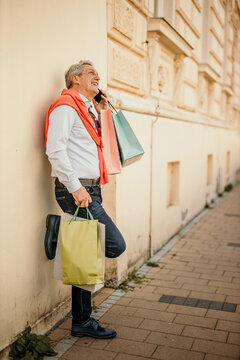 Portrait of a senior man shopping in the city and using a smartphone.