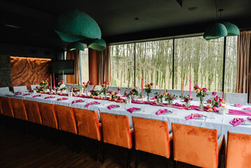 Organized event, served table banquet ready for guests. Decoration with pink, orange flowers roses, candles, fruits for birthday party, wedding reception. Luxury elegant setting dinner in a restaurant