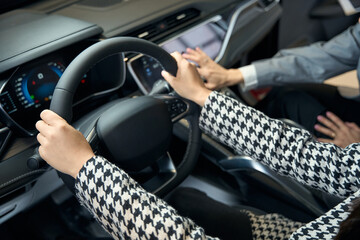 Female hands in a jacket on the steering wheel