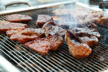 Seasoned pork ribs being grilled on a charcoal brazier - obrazy, fototapety, plakaty